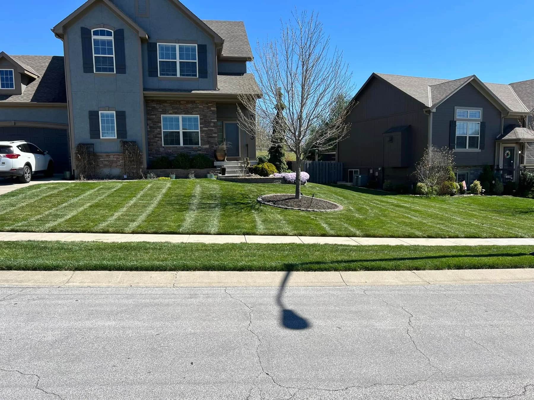 Fresh parallel lawn stripes in front of a neighborhood home