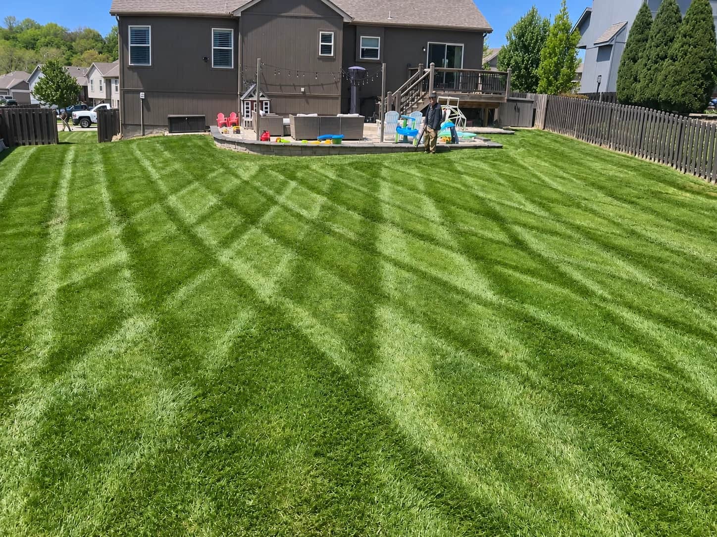 Fresh mowing stripes across a backyard lawn beside a house and patio